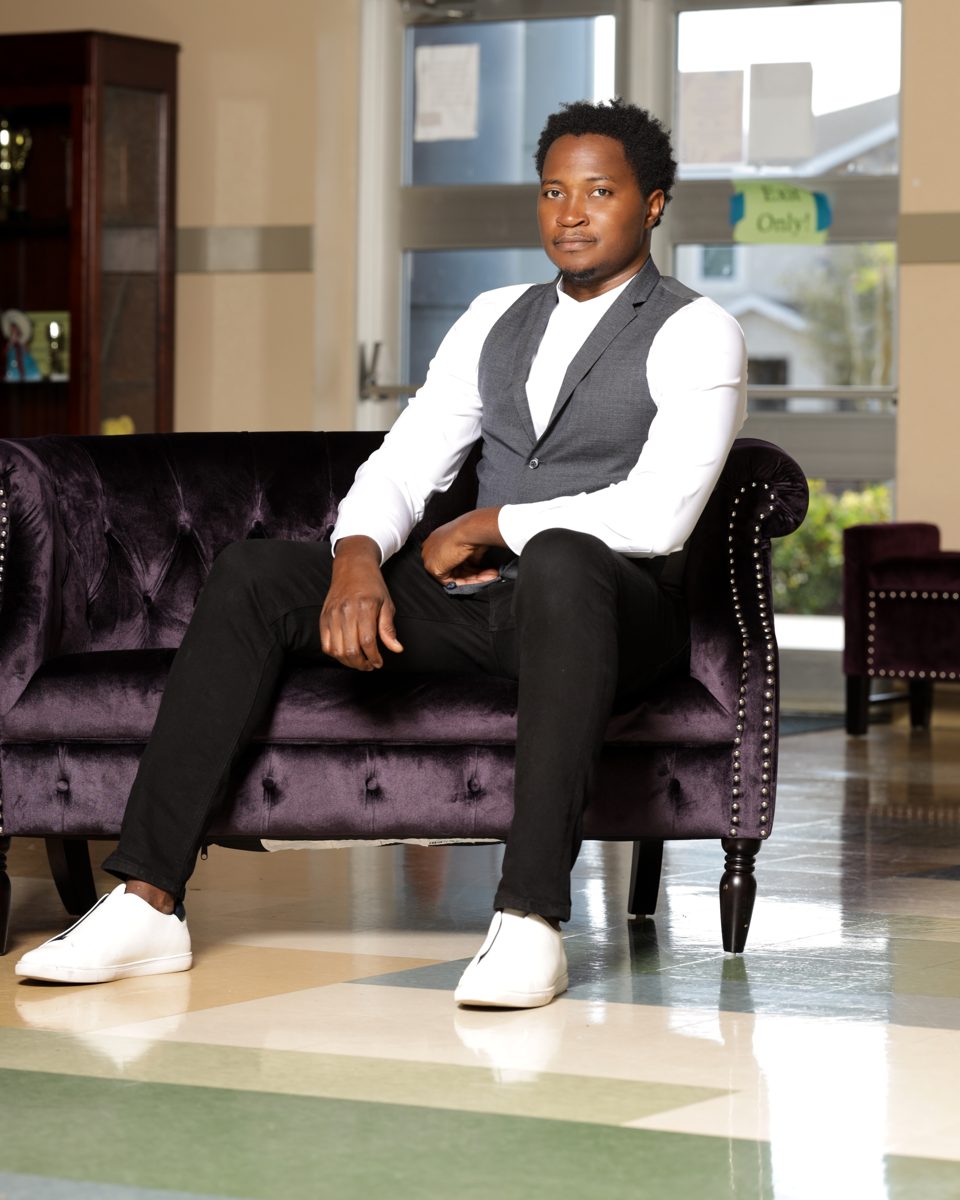 Truman Rexti seated on a velvet sofa in a school lobby